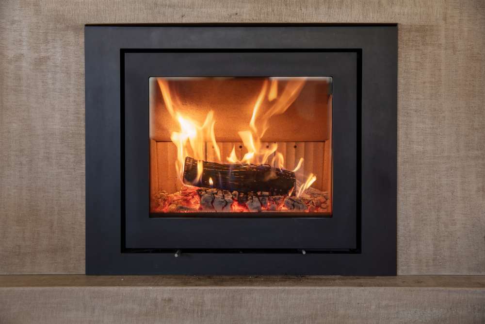 Ein brennendes Holzscheit in einem modernen Kamin mit schwarzem Rahmen.